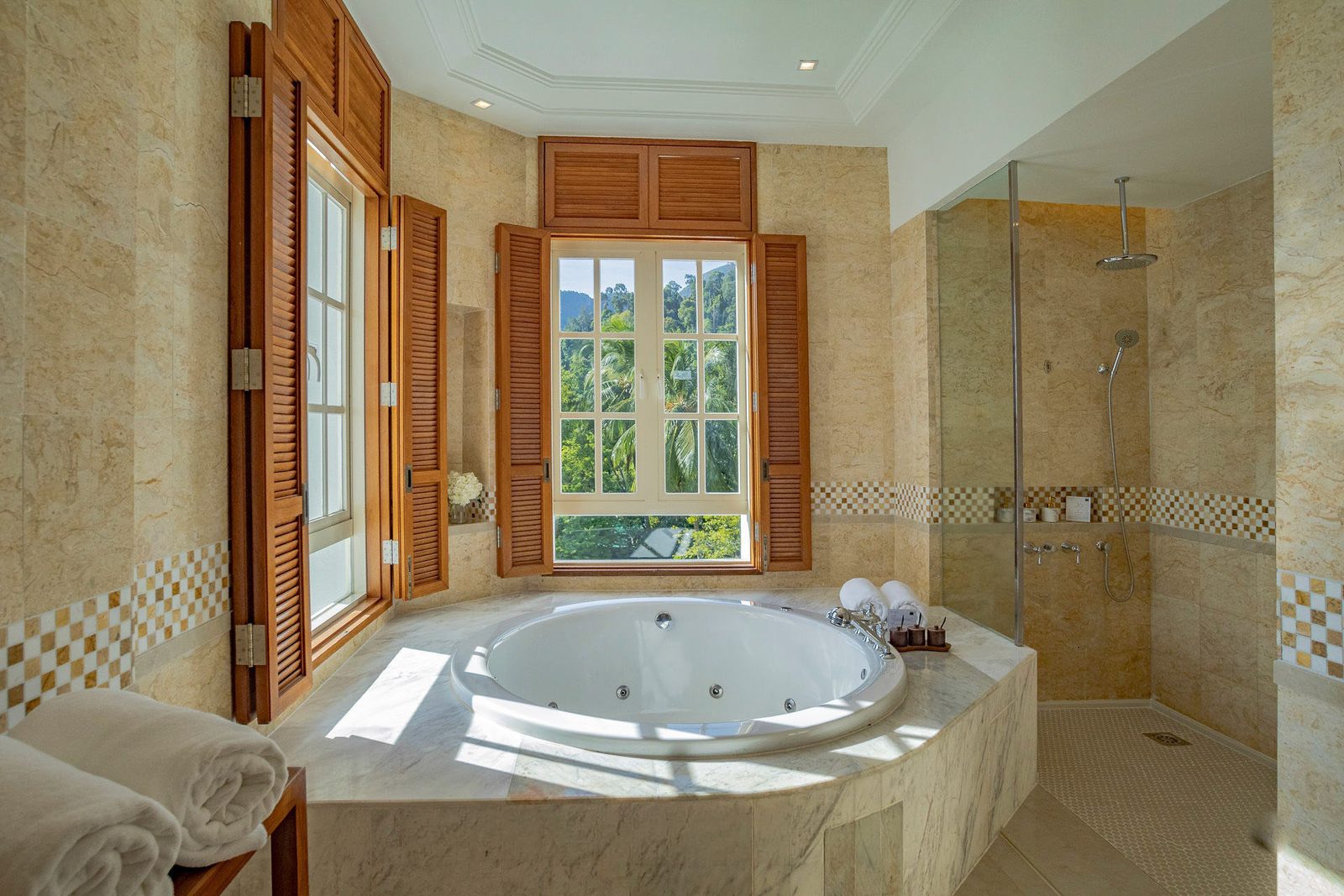 Marble bathroom with sunken tub, timber louvred shutters and jungle outlook