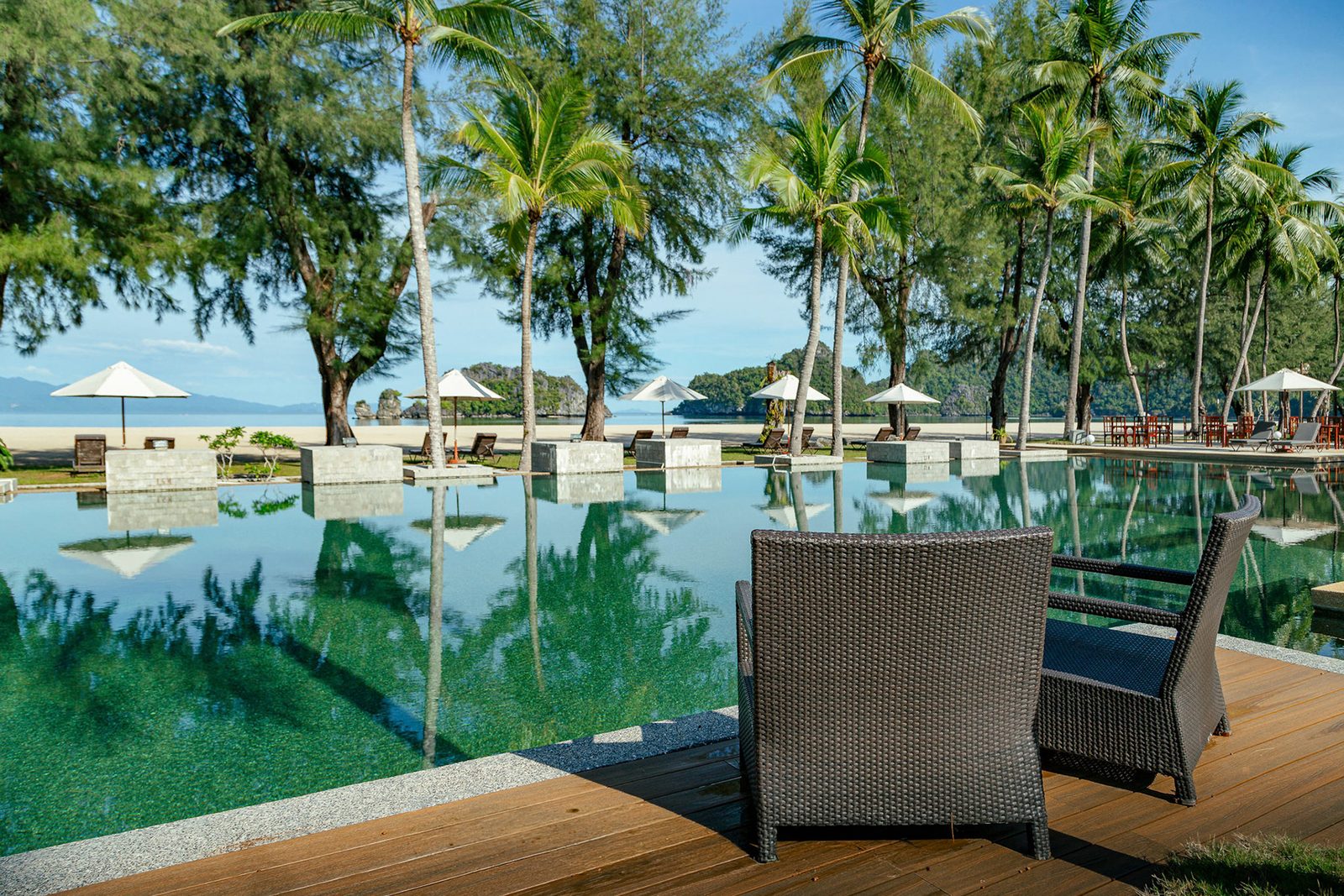 Resort pool and palm grounds with beach and limestone karst islands beyond