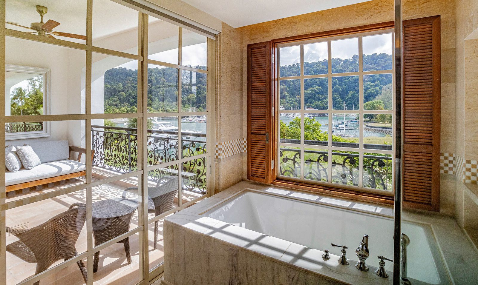 Marble bathroom behind a glazed partition, shuttered window looking out to a marina