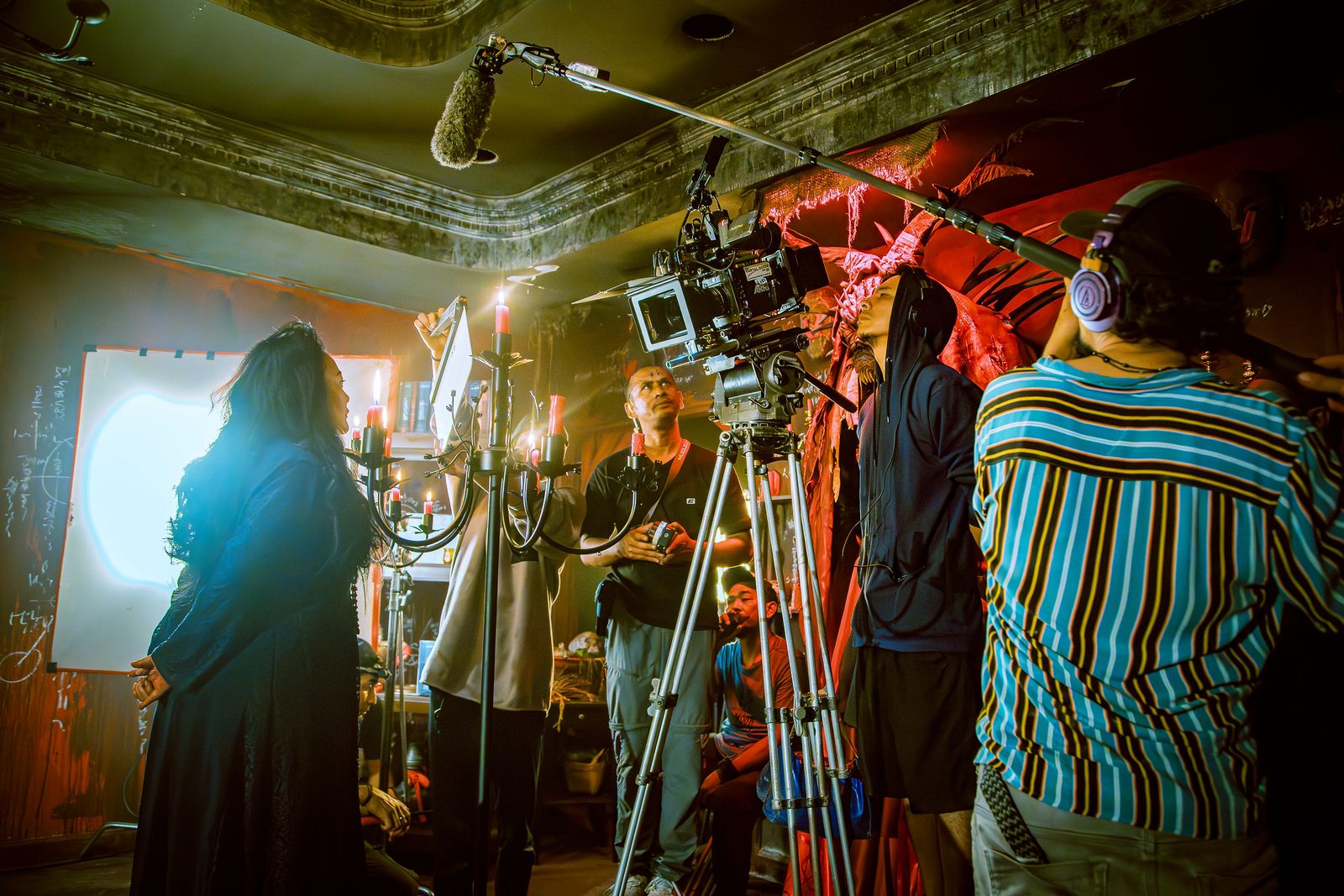 Crew with boom microphone and lighting rig working around the set