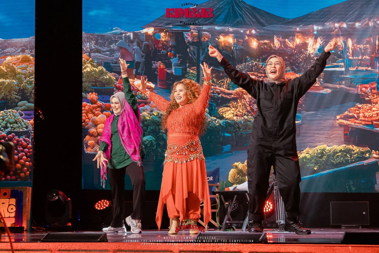 Performers in costume on stage against a painted market backdrop