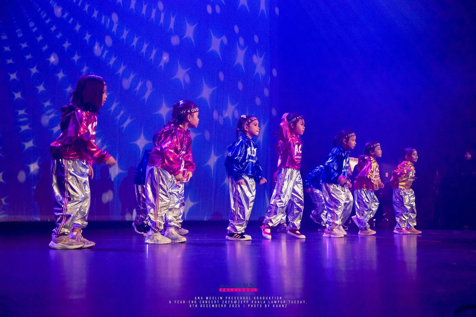 Dancers in metallic costumes on a blue-lit stage