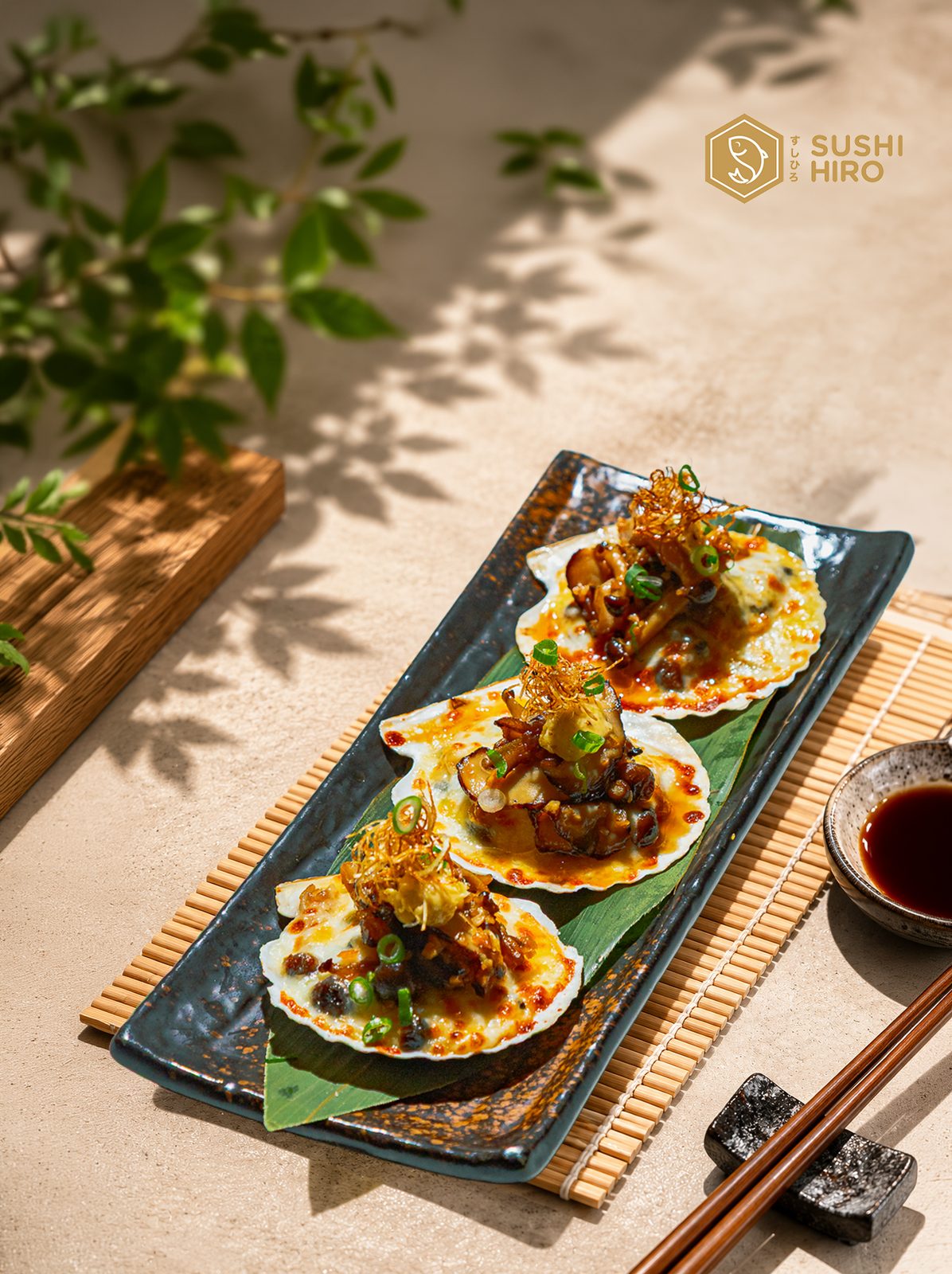 Three baked scallops on a ceramic plate in dappled sunlight
