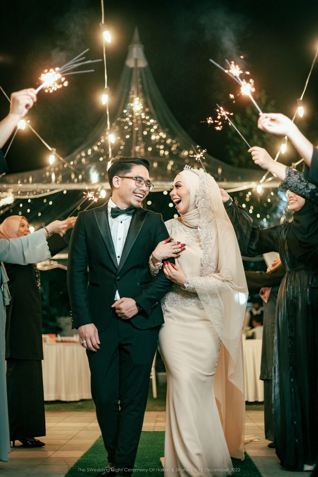 Couple walking through an arch of sparklers at a night reception