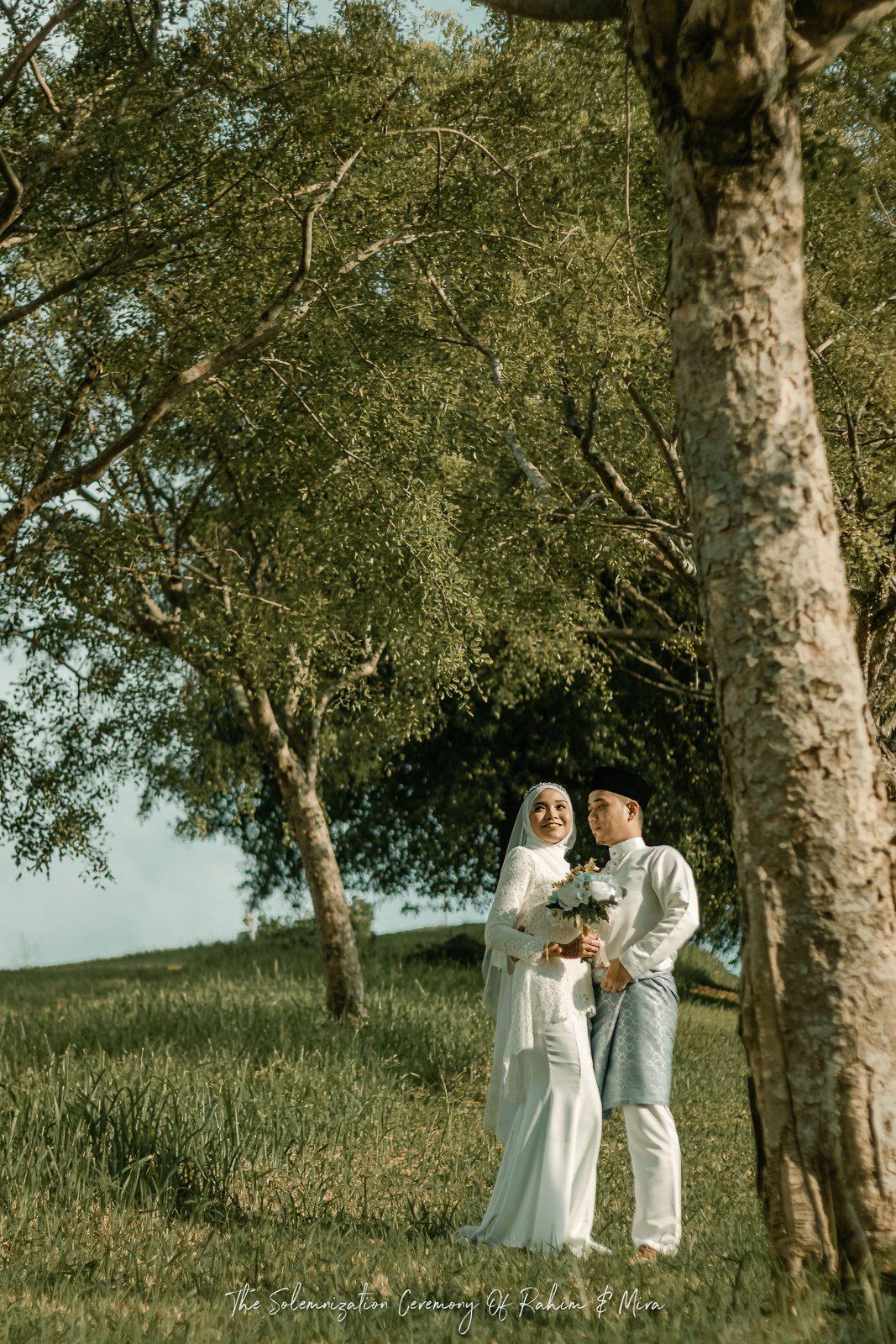 Couple photographed outdoors beneath a tree